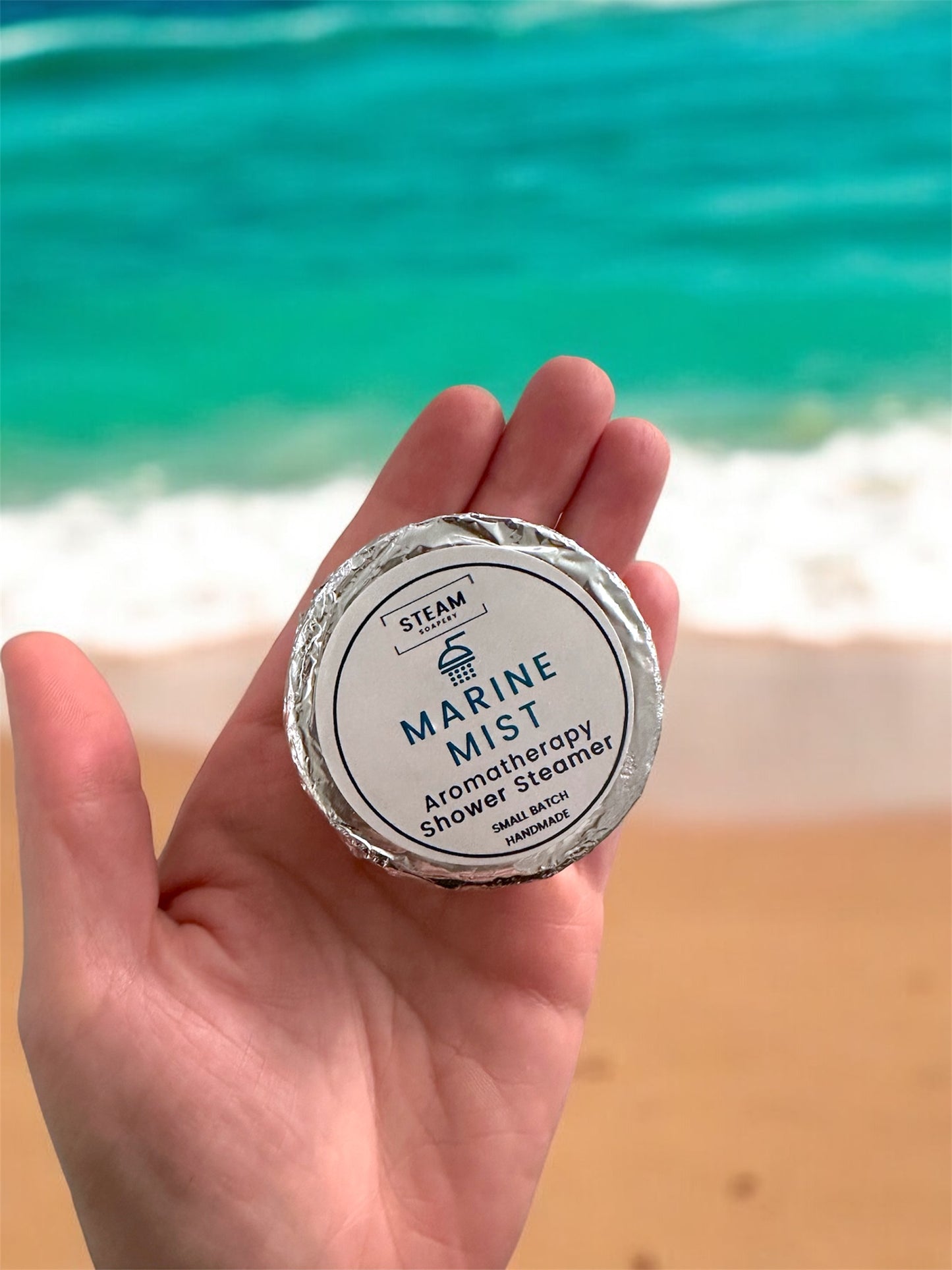 Marine Mist Shower Steamer on Hand above Ocean