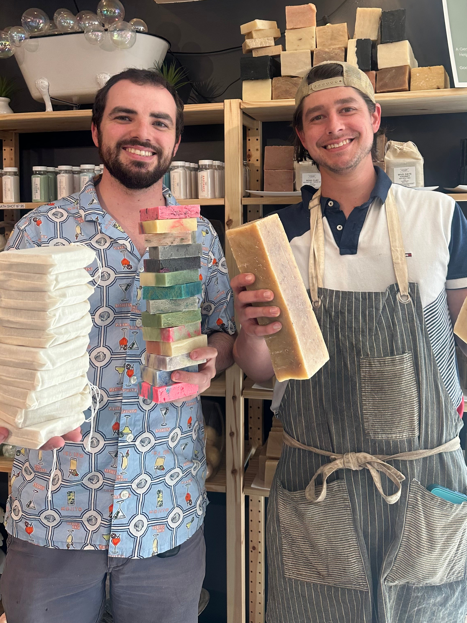 Two men holding stacks of soap bars in a store setting